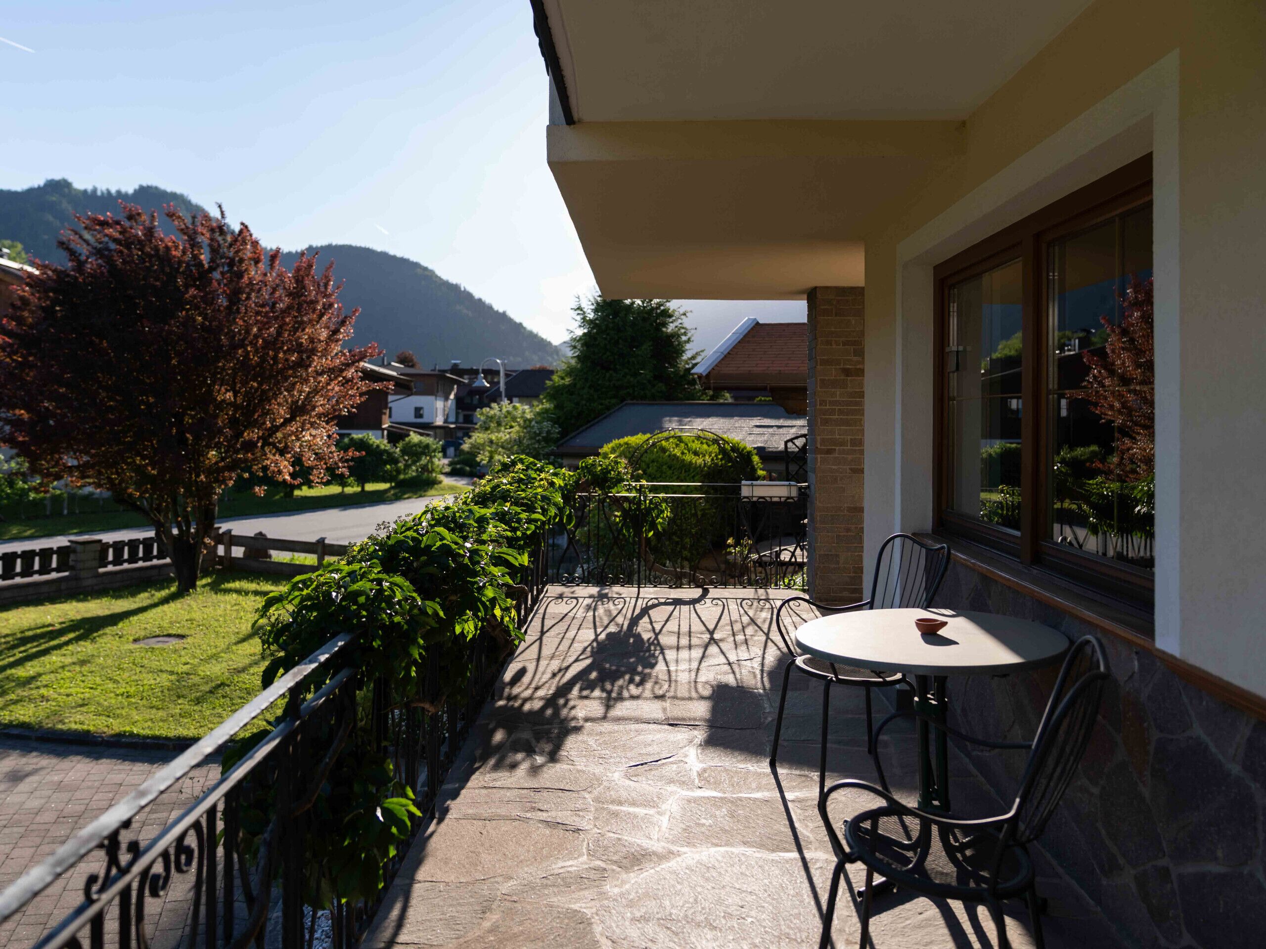 Un balcon avec un sol en pierre, une table et des chaises.