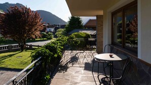 Un balcone con pavimento in pietra, un tavolo e delle sedie.