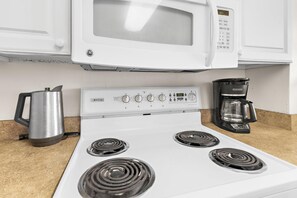 Uma cozinha com forno autolimpante GE, cafeteira e chaleira.
