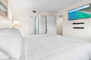 Quarto de hotel com uma cama, uma televisão na parede e um quadro na parede.