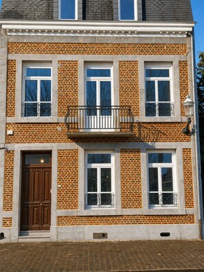 Um edifício de dois andares com fachada de tijolos, janelas emolduradas por branco e porta de madeira.