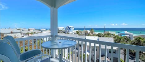 Ein Balkon mit Tisch und Stühlen mit Blick auf Strand und Meer.