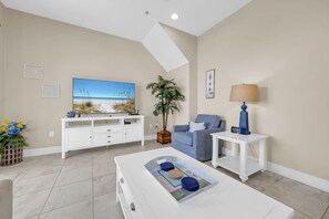 A living room with a flat-screen TV, a sofa, a coffee table, a lamp, and a plant. - Sunny Beach Days (Panama City Beach)