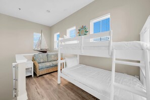 A room with bunk beds, a desk, a chair, and a sailboat model. - Sunny Beach Days (Panama City Beach)