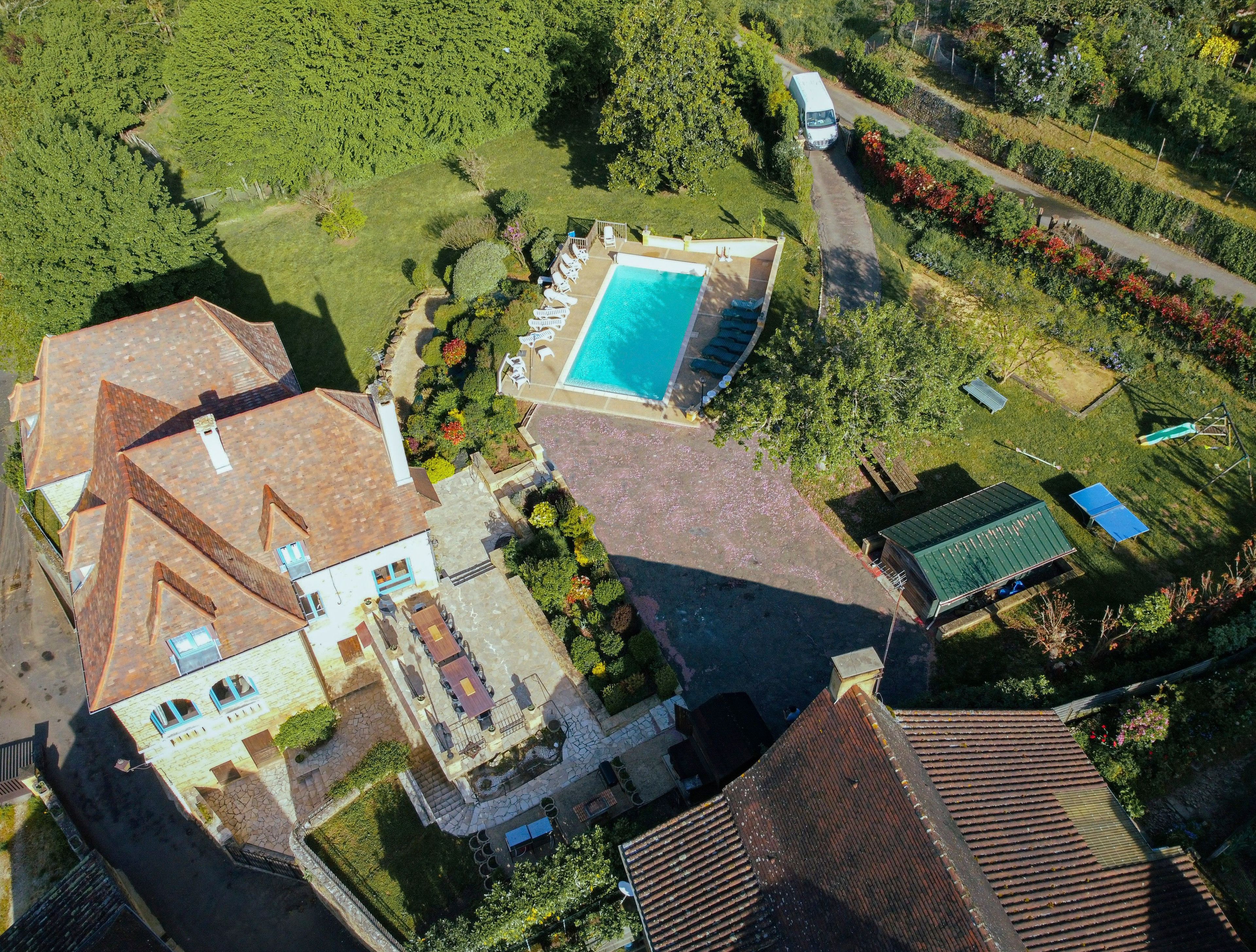 Vue aérienne d’une propriété comprenant une piscine, plusieurs bâtiments et un espace vert environnant.