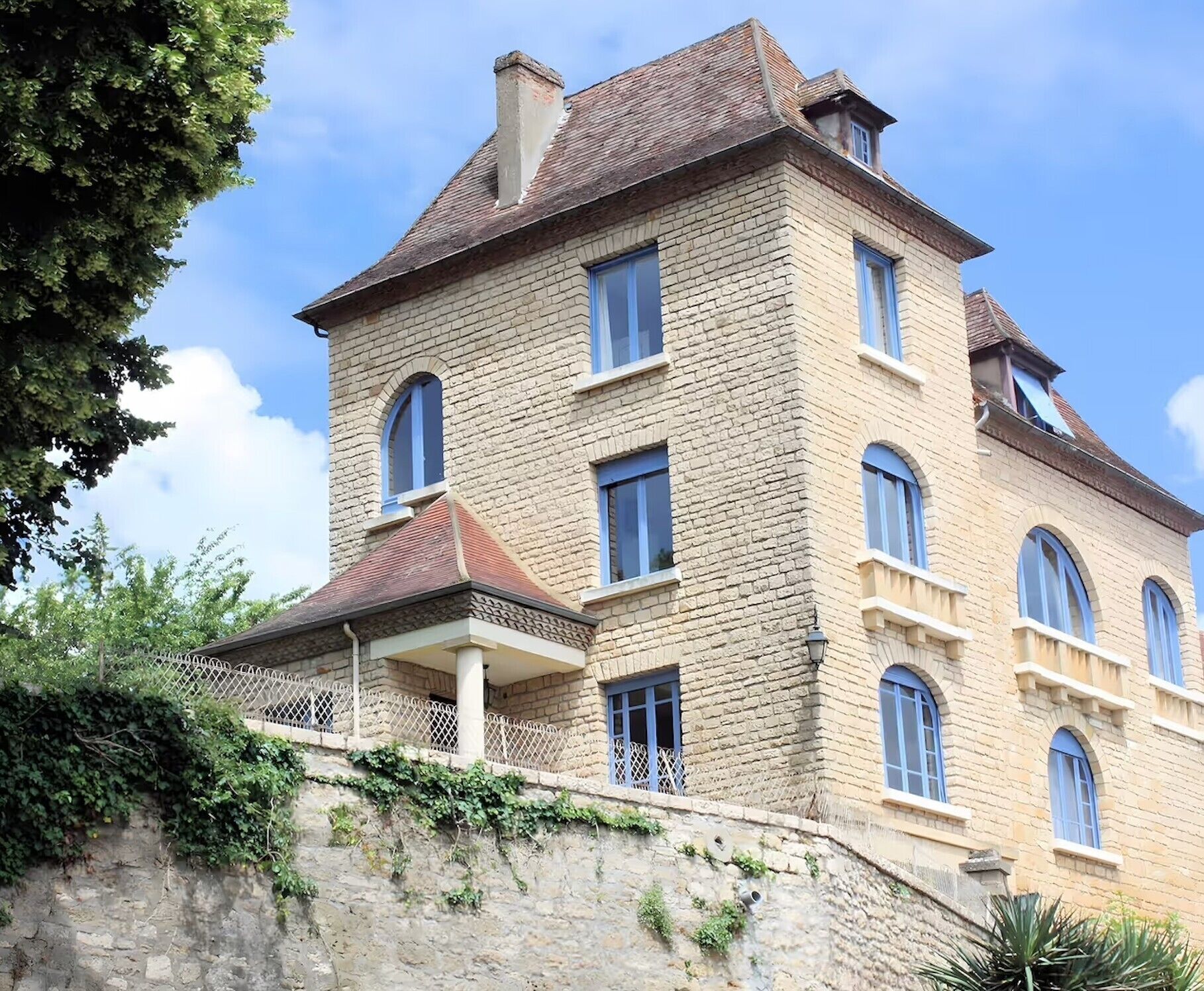 A multi-story stone building with a balcony and a stone wall.