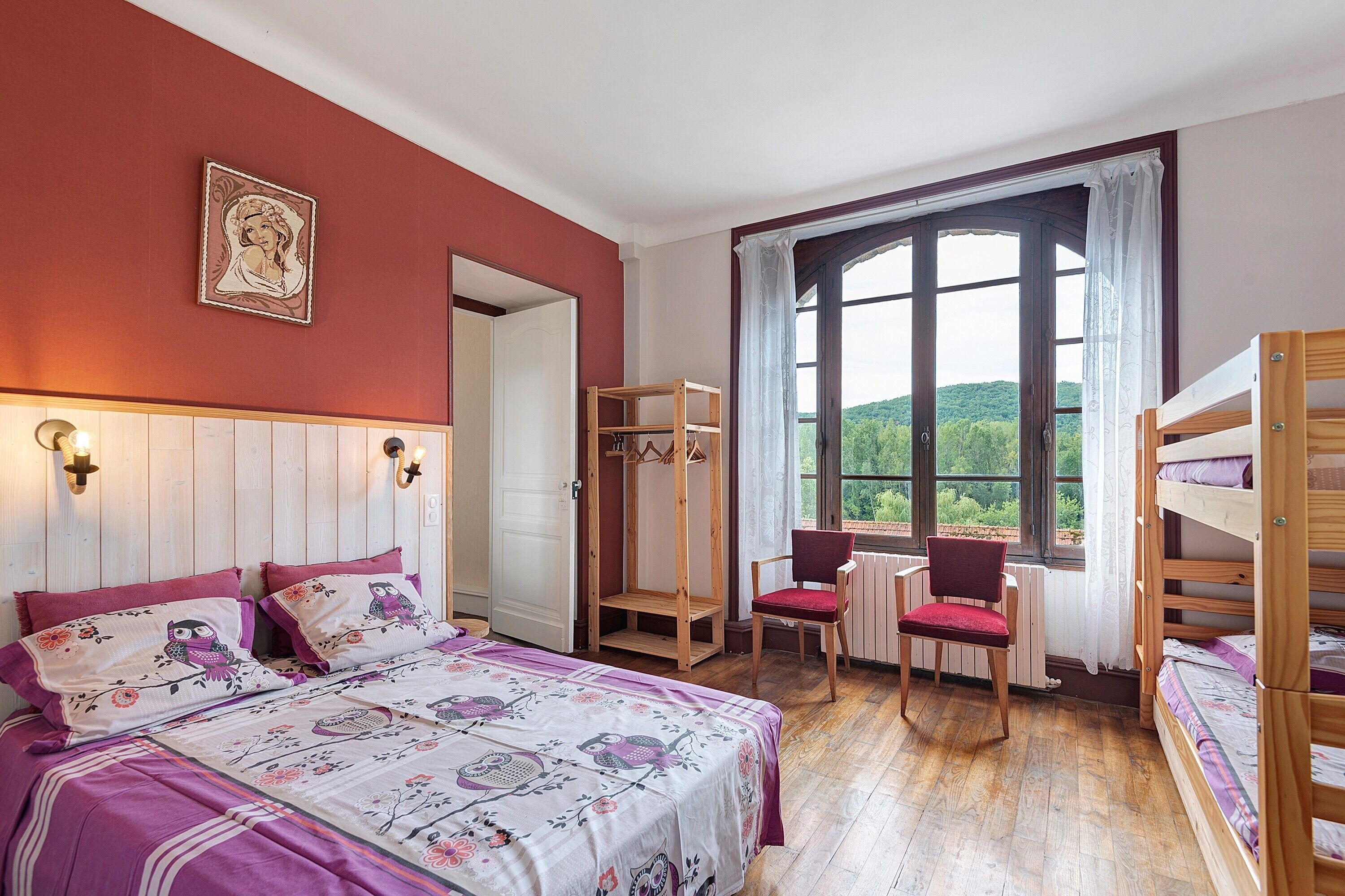 Une chambre à coucher avec un lit, une chaise, une armoire en bois et une fenêtre donnant sur un beau paysage.