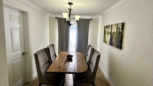 Ein Essbereich mit Holztisch und Stühlen, einer Kristallleuchtre und einem Gemälde an der Wand.