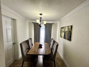 Ein Essbereich mit Holztisch und Stühlen, einer Kristallleuchtre und einem Gemälde an der Wand.