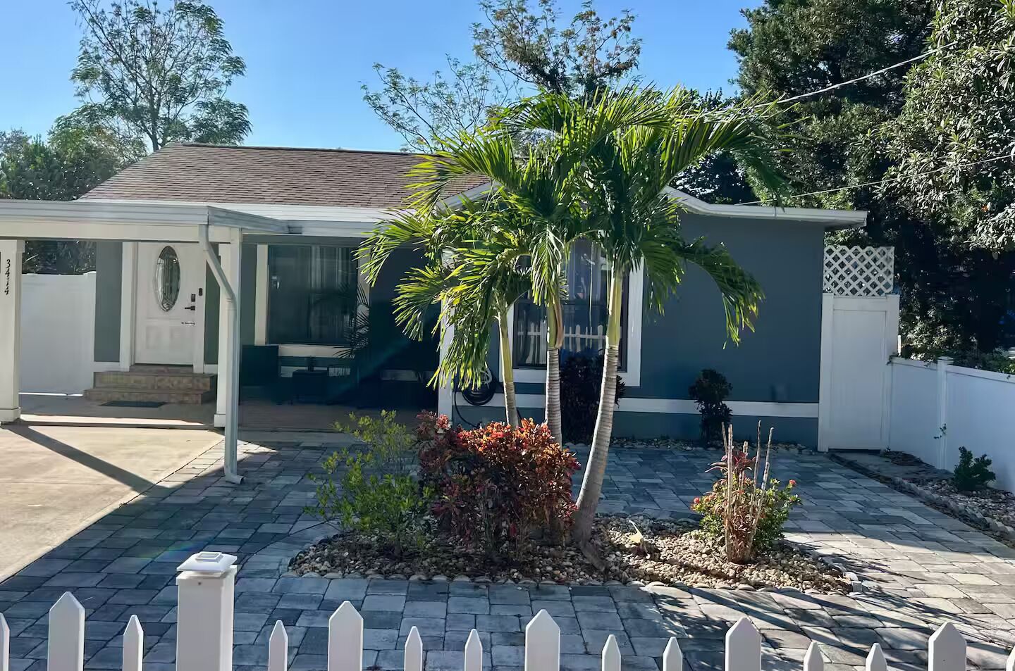 A residential house with a covered porch, a palm tree, and a small garden area.