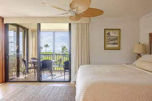 A hotel room with a bed, a ceiling fan, a view of the outdoors, and a balcony with chairs. - Wake up to breathtaking direct Gulf-front views at Loggerhead Cay 142. This beautifully updated 2-bedroom, 2-bath beachfront condo sleeps 5 and includes beach gear, a heated pool, pickleball, and everything you need for the perfect Sanibel getaway. (Sanibel Island)