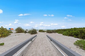 A beach pathway leading to the ocean, surrounded by vegetation and a clear sky. - Wake up to breathtaking direct Gulf-front views at Loggerhead Cay 142. This beautifully updated 2-bedroom, 2-bath beachfront condo sleeps 5 and includes beach gear, a heated pool, pickleball, and everything you need for the perfect Sanibel getaway. (Sanibel Island)