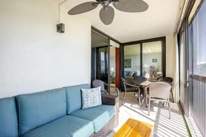 Un balcon équipé d’un canapé, d’une table à manger, de chaises et d’un ventilateur de plafond.