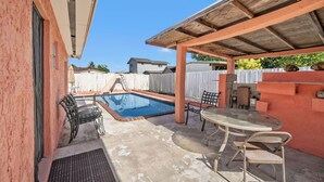 A backyard with a swimming pool, outdoor furniture, and a covered patio area. - Miami Gardens Pool Retreat (Miami Gardens)