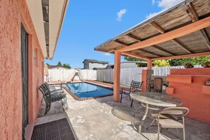 A backyard with a swimming pool, outdoor furniture, and a covered patio area. - Miami Gardens Pool Retreat (Miami Gardens)