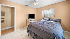 A bedroom with a bed, a television on a stand, a ceiling fan, and a window with blinds. - Miami Gardens Pool Retreat (Miami Gardens)