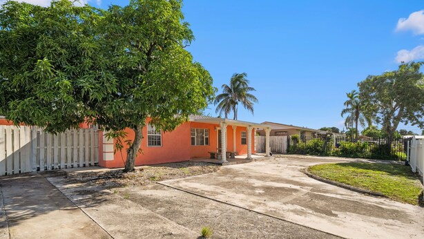 A residential property with a paved driveway, a tree, and a fenced yard. - Miami Gardens Pool Retreat (Miami Gardens)