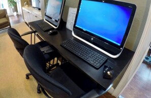 Ein Arbeitsplatz mit zwei Laptops, einem Desktop-Computer, einer Tastatur und einer Maus auf einem Schreibtisch.