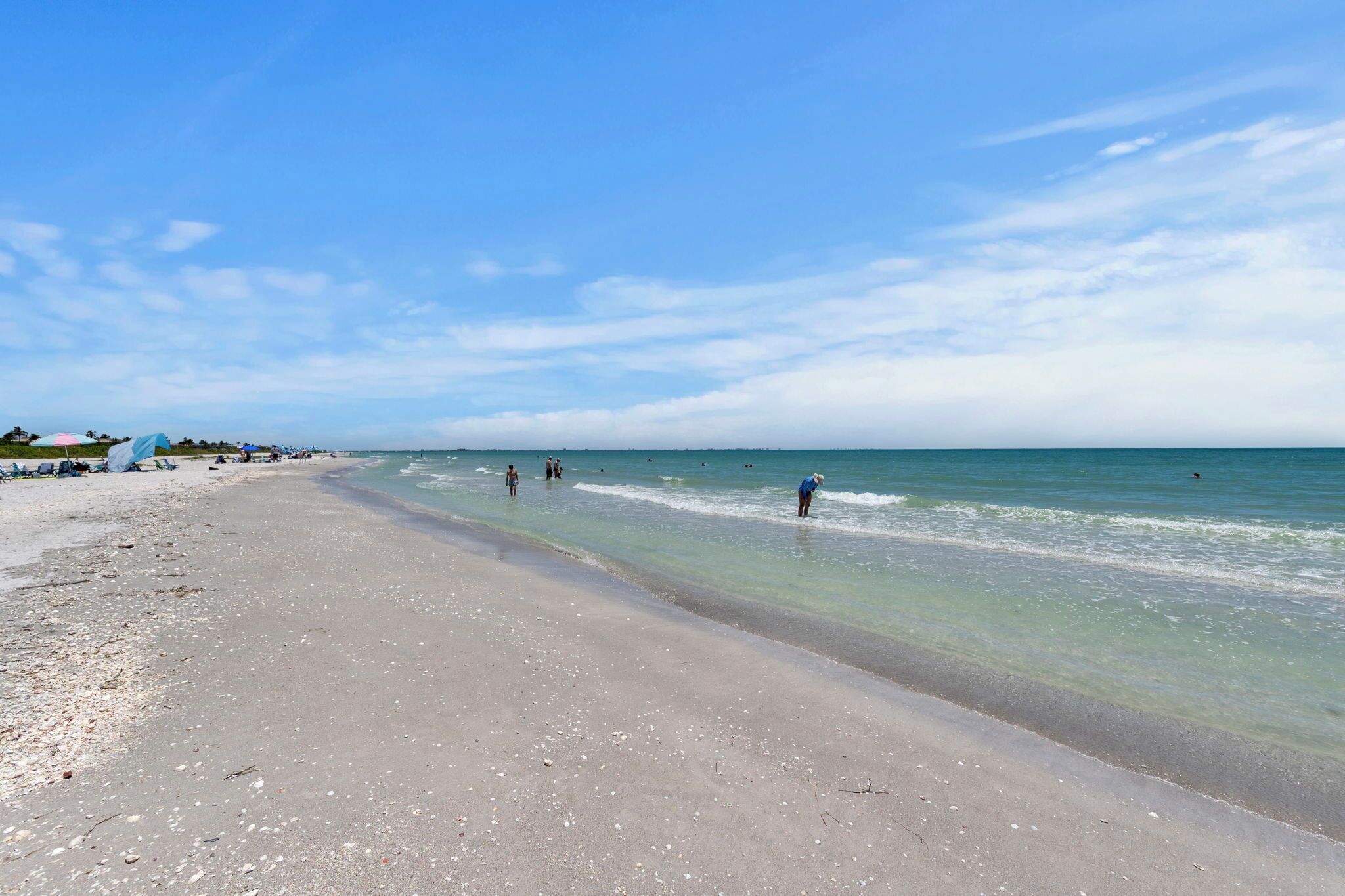 A beach with clear water, a sandy shore, and umbrellas.