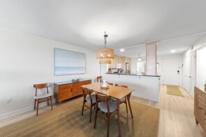 A modern kitchen with a dining area, wooden furniture, and a large window. - Wake up to Gulf views at Loggerhead Cay 584, a top-floor 2BR/2BA Sanibel condo overlooking the pool with beautiful side Gulf views + additional water views from the guest bedroom. Enjoy direct beach access, heated pool, tennis/pickleball and more (Sanibel Island)