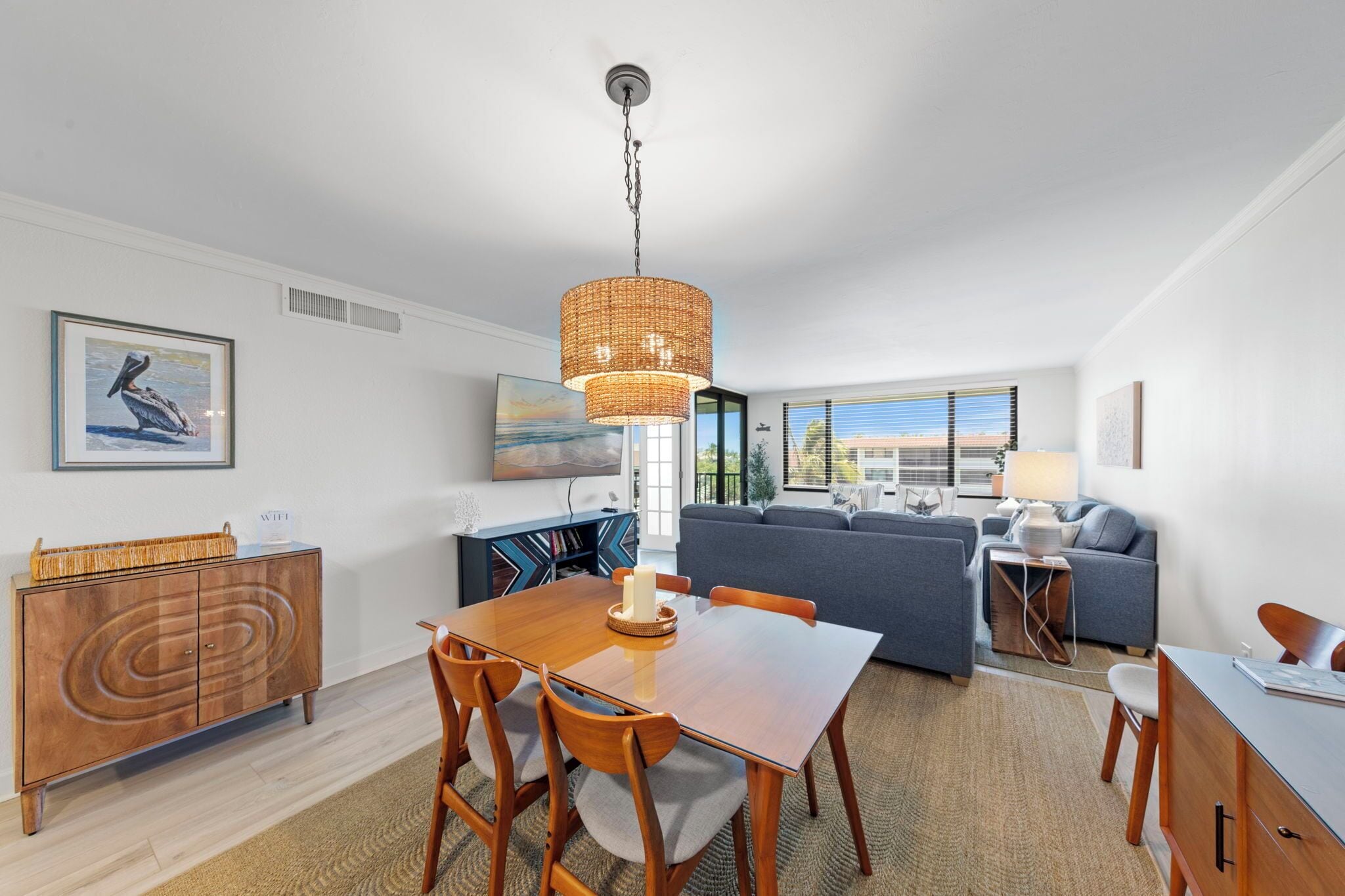 A modern living room with a dining area, a sofa set, and a large window with blinds.