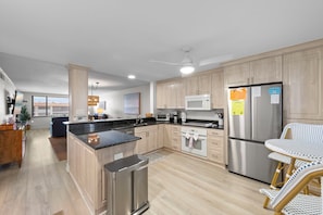 A modern kitchen with a central island, stainless steel appliances, and light wood cabinetry. - Wake up to Gulf views at Loggerhead Cay 584, a top-floor 2BR/2BA Sanibel condo overlooking the pool with beautiful side Gulf views + additional water views from the guest bedroom. Enjoy direct beach access, heated pool, tennis/pickleball and more (Sanibel Island)