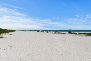 A wide sandy beach with a clear sky and calm sea. - Wake up to Gulf views at Loggerhead Cay 584, a top-floor 2BR/2BA Sanibel condo overlooking the pool with beautiful side Gulf views + additional water views from the guest bedroom. Enjoy direct beach access, heated pool, tennis/pickleball and more (Sanibel Island)