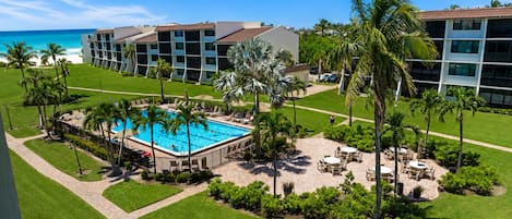 Un resort con piscina central, palmeras y vista al océano.