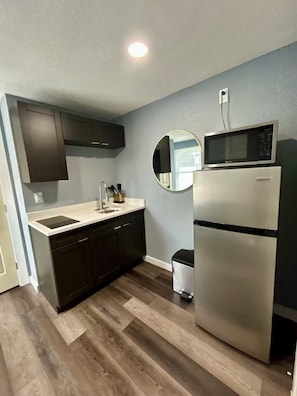 A compact kitchen with a built-in dishwasher, a stainless steel refrigerator, and a microwave. - Sunshine Guest Cottage (Tampa)