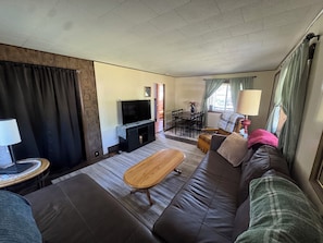 Una sala de estar con sofá, mesa de centro, televisor y un comedor con sillas y mesa.