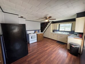 A compact kitchen with a refrigerator, stove, and wooden flooring.