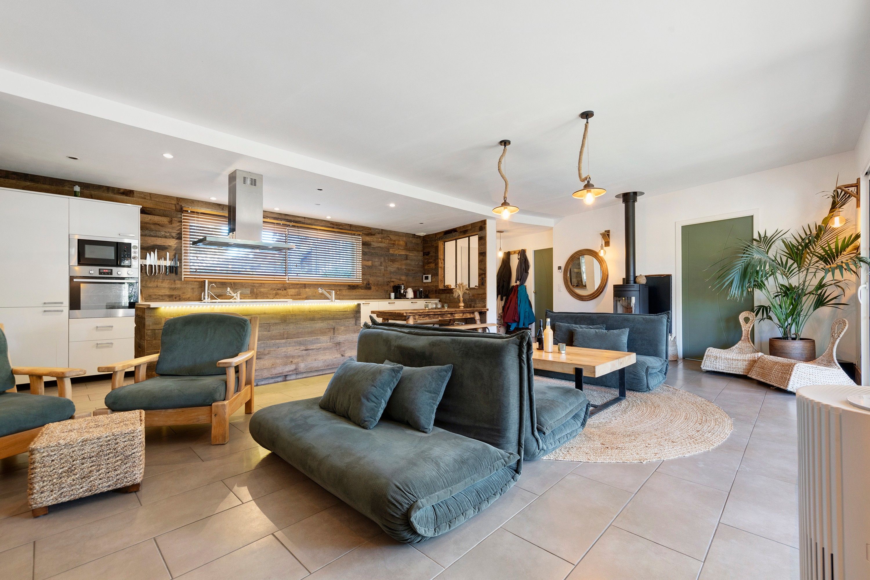 A modern living room with a sofa, chairs, a dining table, and a kitchen area with appliances.