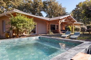 Une maison avec une piscine, un patio couvert et un jardin.