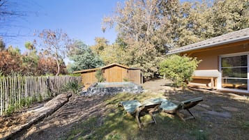 A backyard with a wooden deck, two lounge chairs, a hot tub, and a wooden fence.
