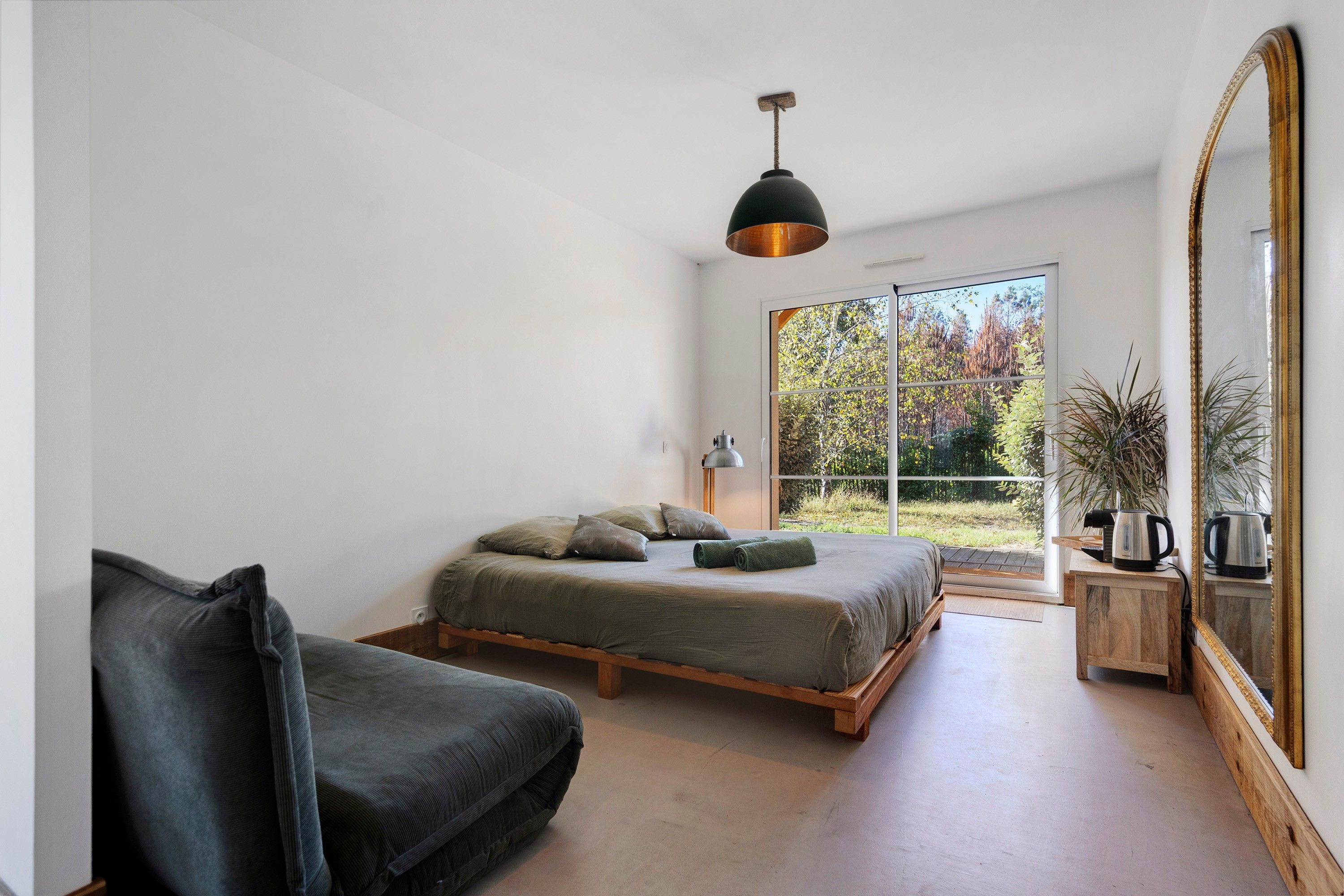 Une chambre à coucher moderne, avec un lit, une chaise, un grand miroir et une vue sur l’extérieur.