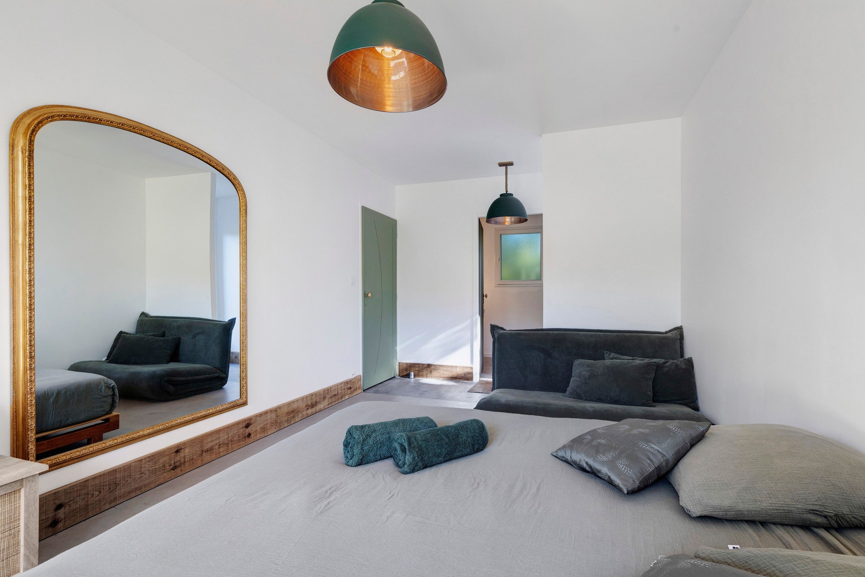 Ein modernes Schlafzimmer mit einem großen Bett, einem Spiegel und zwei Pendelleuchten.
