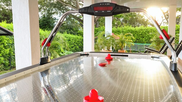 A pool table with a digital scoreboard and a view of greenery outside.