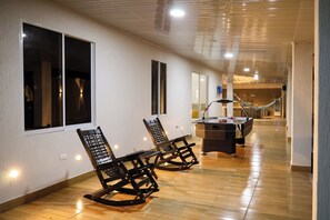 A corridor with wooden flooring, a pool table, and two rocking chairs. - Area 89. Stunning Villa—Pool, Hot Tub, and Home Theater, Just 5 Minutes from the Hot Springs (Rivera)