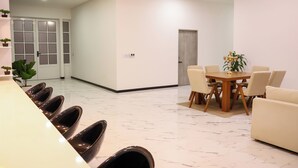 A modern dining area with a marble floor, a round table, and six chairs.