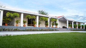 A modern building with a covered walkway, potted plants, and a well-maintained lawn.