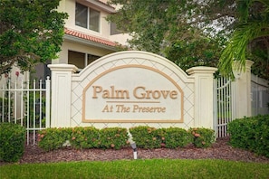 Een hekpoort met een bord waarop staat 'Palm Grove At The Preseroe'.