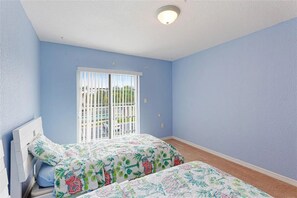 Een slaapkamer met twee bedden, een raam met uitzicht en een plafondlamp.