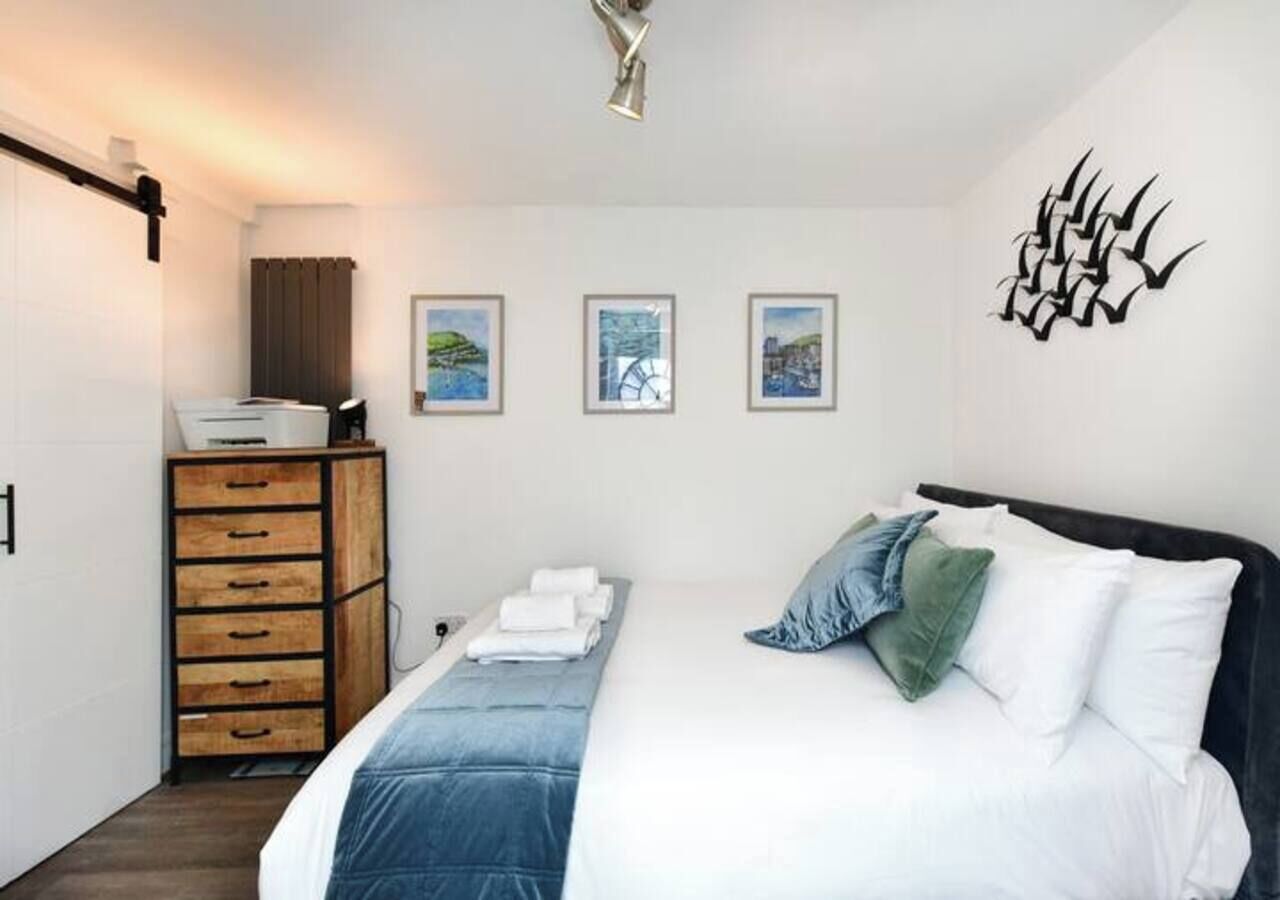 A bedroom with a bed, a dresser, and wall art.