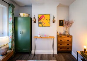 A room with a green cabinet, a wooden dresser, a table with decorative items, and wall-mounted sconces. - Modern 2BR Cardiff Home | 2 Bath, Close to Centre - Pass the Keys (Cardiff)