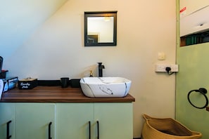 A bathroom with a white marble sink, a black faucet, and a mirror above it. There are cabinets below the sink and a wicker basket to the right.