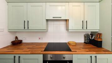 A kitchen with light green cabinets, a wooden countertop, and a built-in oven.