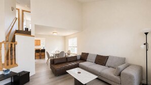 Uma sala de estar ampla com sofá, mesa de centro e mesa de jantar com cadeiras.