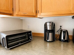 A kitchen with wooden cabinets, a toaster oven, a coffee maker, and a kettle. - Quiet Renton 3BR House near Valley Medical Ctr (Renton)