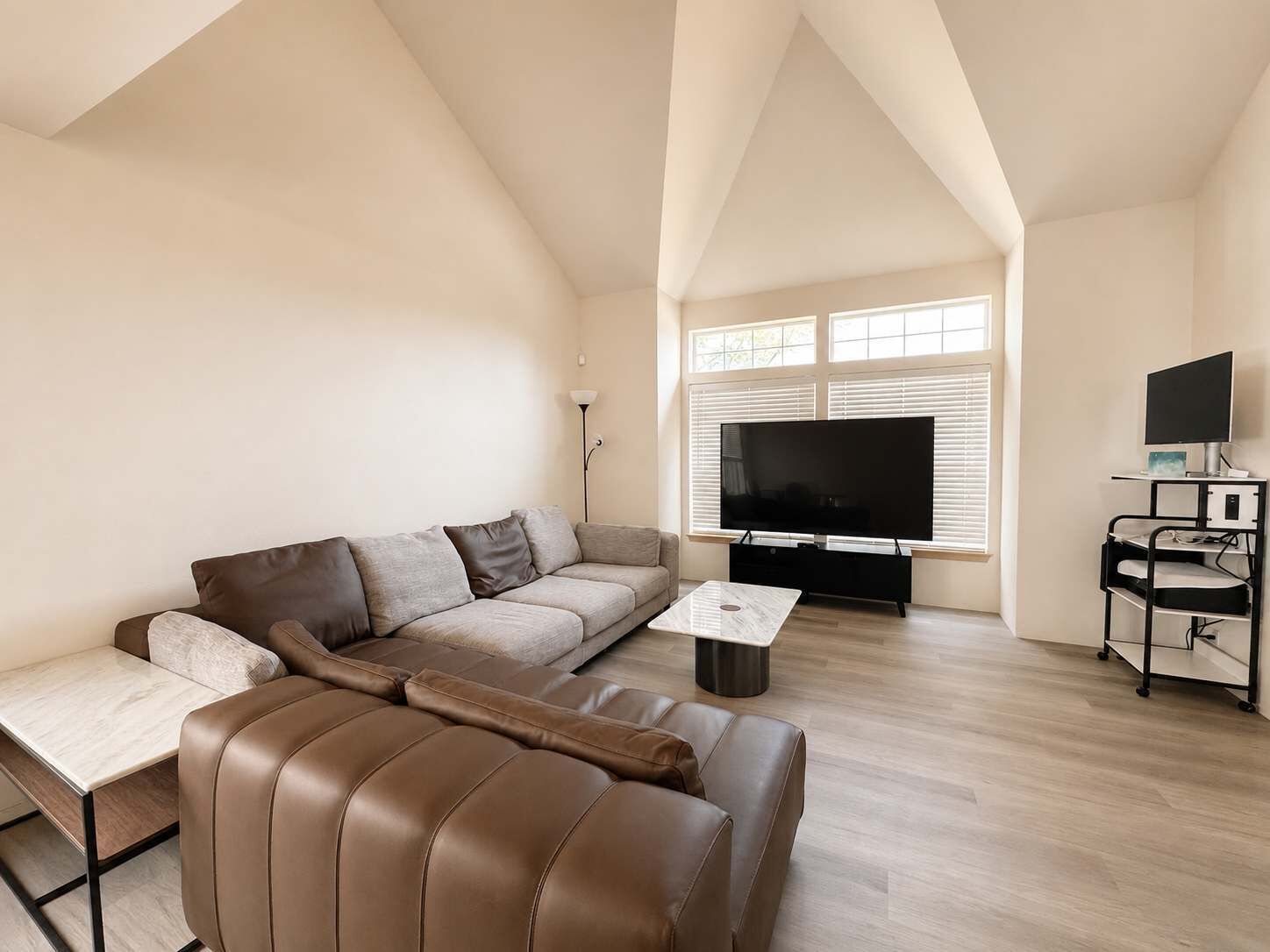 A modern living room with a sofa, coffee table, TV, and a desk with a computer.