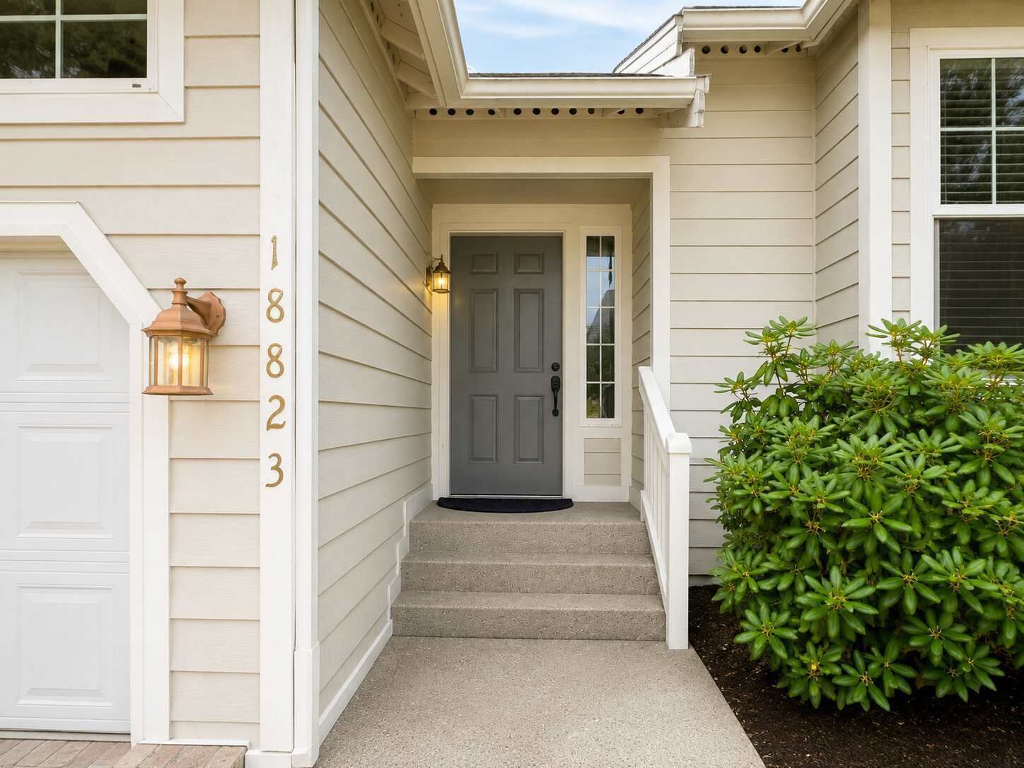 A house with a grey front door, a light fixture, and a number '18823' on the wall.